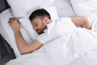 Photo of Handsome man sleeping in soft bed, top view