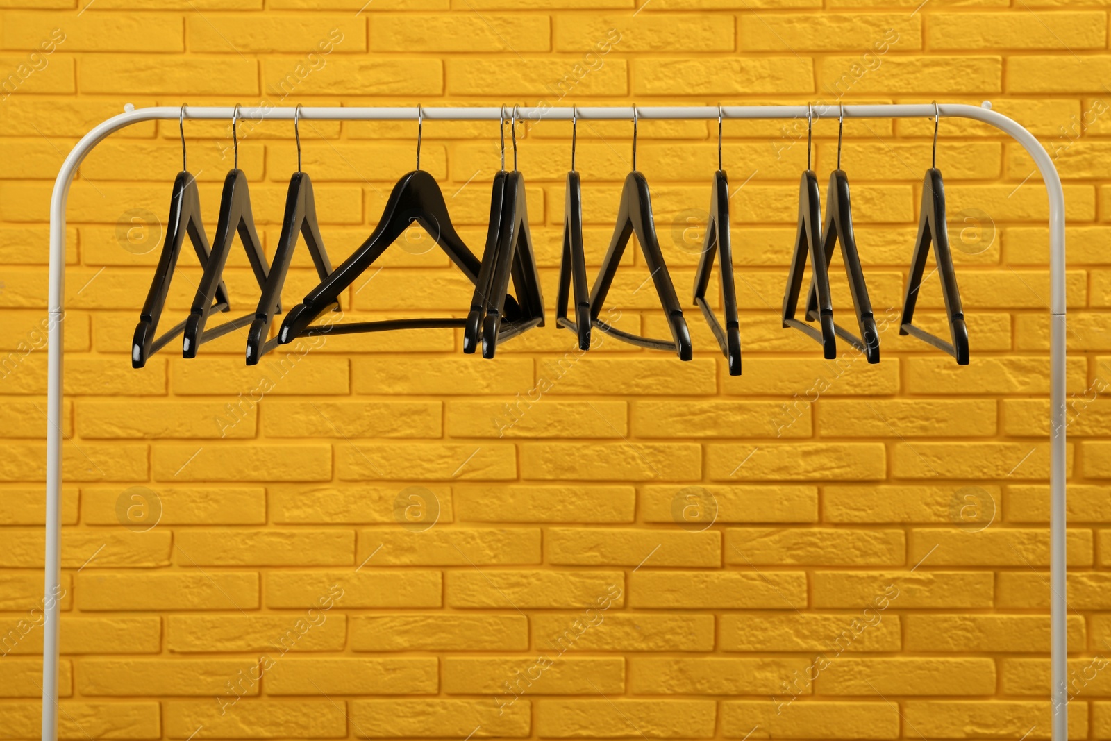 Photo of Wardrobe rack with many hangers near yellow brick wall