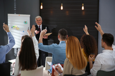 Photo of People raising hands to ask questions at seminar in office