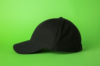 Photo of Stylish black baseball cap on light green background
