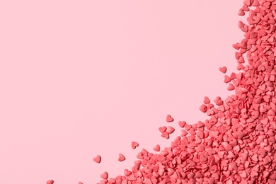 Photo of Heart shaped sprinkles on pink background, flat lay. Space for text