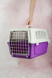 Woman holding violet pet carrier against pink wall, closeup