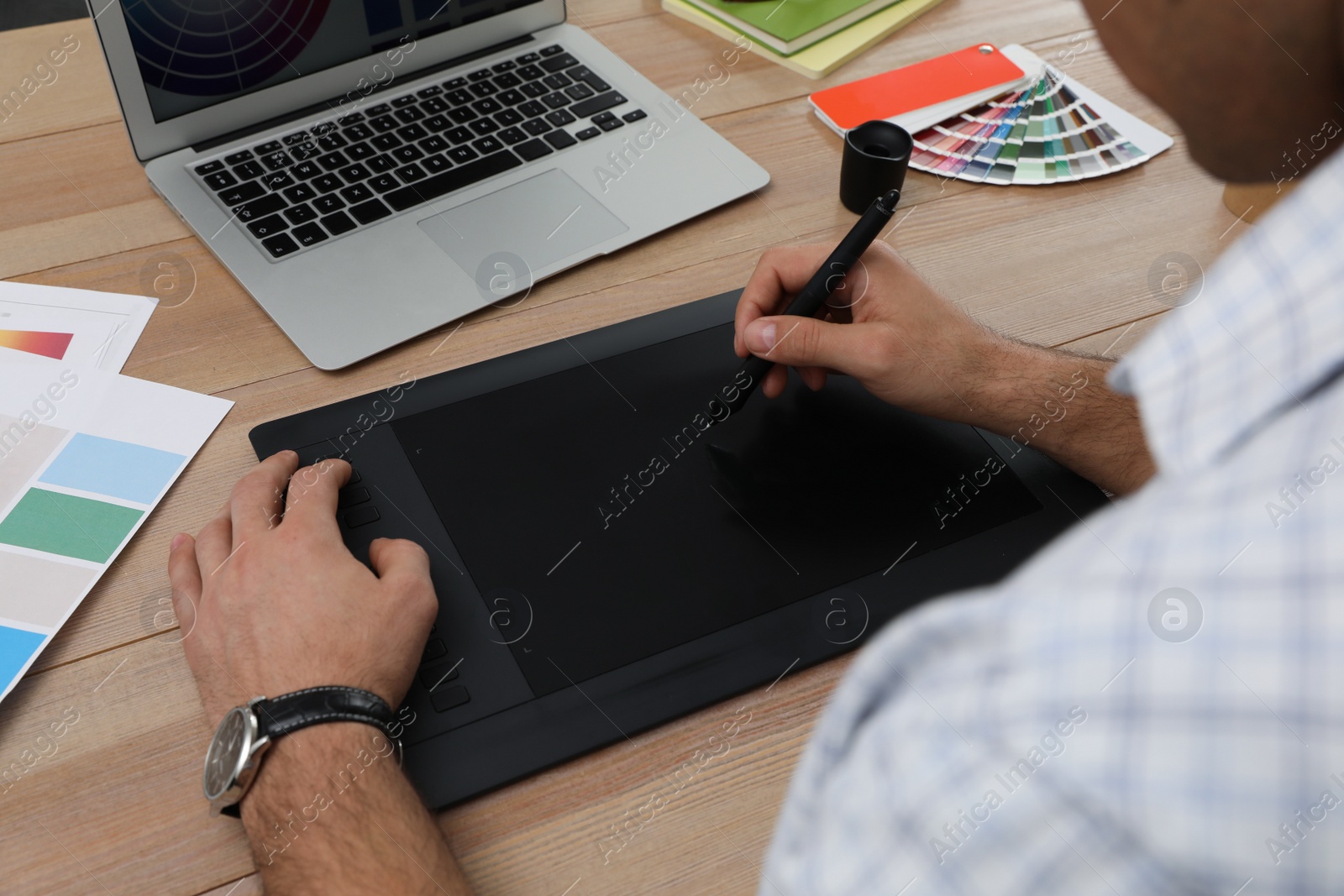 Photo of Professional designer with graphic tablet at wooden table, closeup