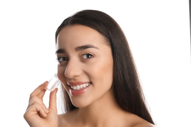 Photo of Young woman with ice cube on white background. Skin care