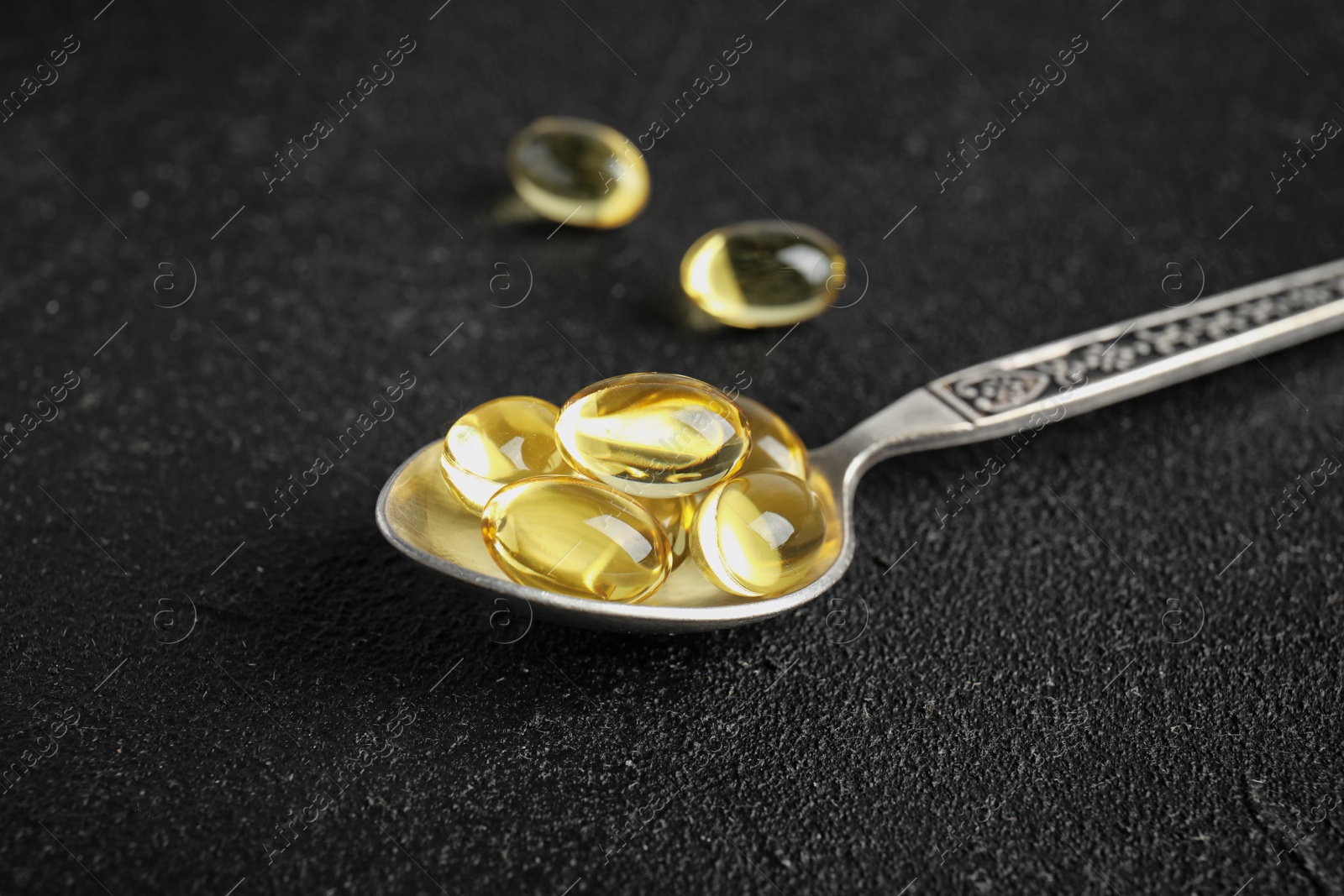 Photo of Spoon with cod liver oil pills on table, closeup