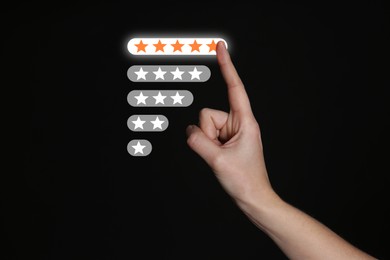 Image of Woman choosing five stars on virtual screen against black background, closeup