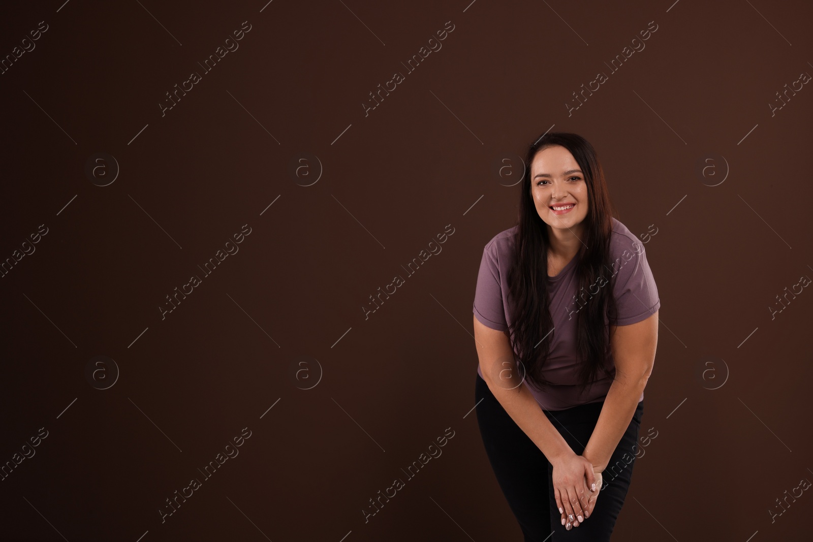 Photo of Beautiful overweight woman with charming smile on brown background. Space for text