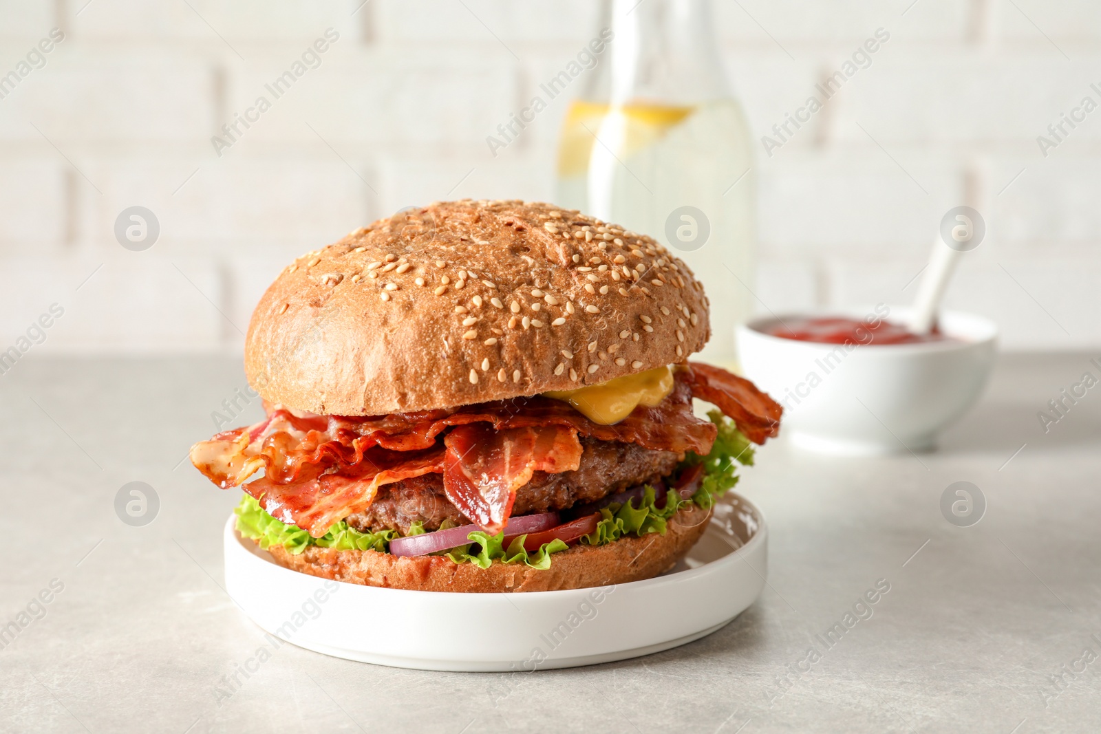 Photo of Tasty burger with bacon on table