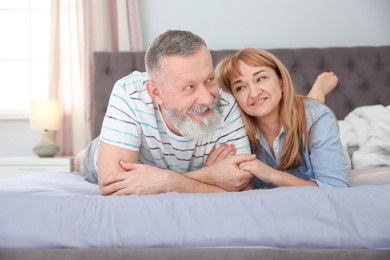 Mature couple together on bed at home