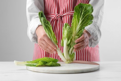 Photo of Woman with fresh cabbage at white table, closeup