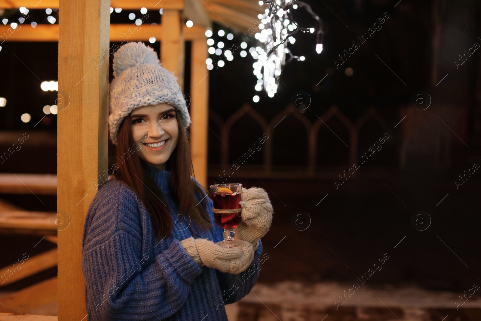 Photo of Woman with glass cup of mulled wine at winter fair. Space for text