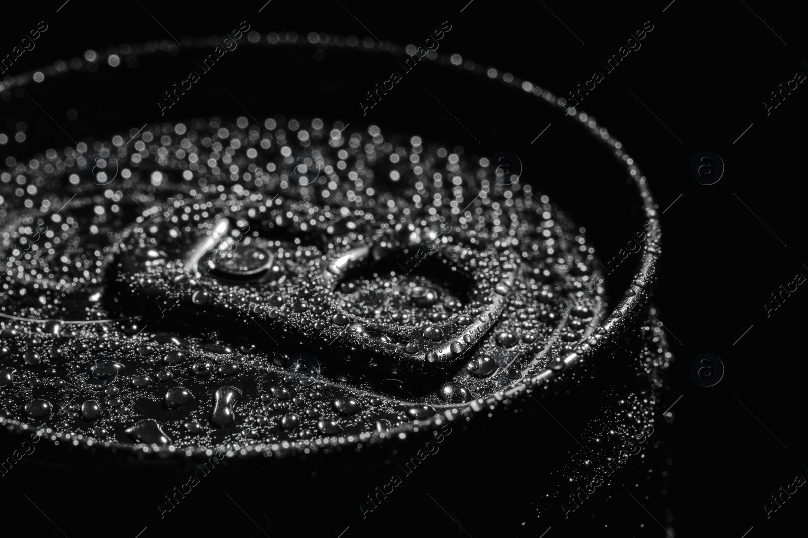 Photo of Aluminum can of beverage covered with water drops on black background, closeup