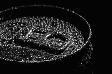 Photo of Aluminum can of beverage covered with water drops on black background, closeup