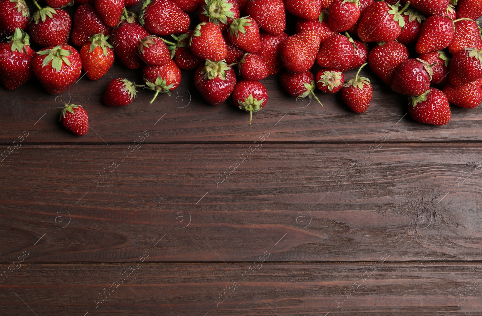 Photo of Delicious ripe strawberries on wooden table, flat lay. Space for text