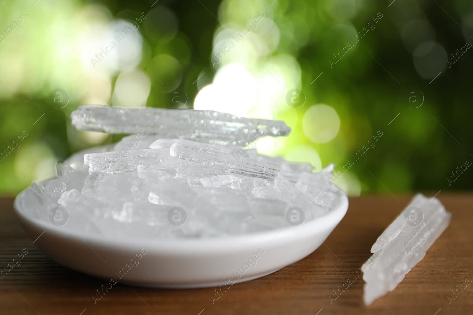 Photo of Menthol crystals on wooden table against blurred background, closeup