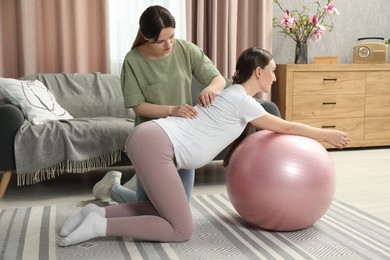 Doula massaging pregnant woman at home. Preparation for child birth