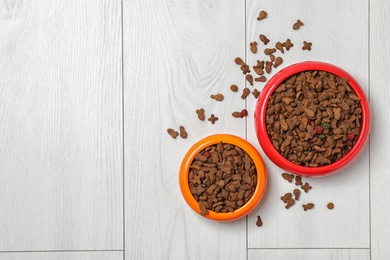 Bowls with food for cat and dog on wooden background. Pet care