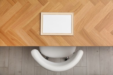 Photo of Empty photo frame on wooden table near chair indoors, top view