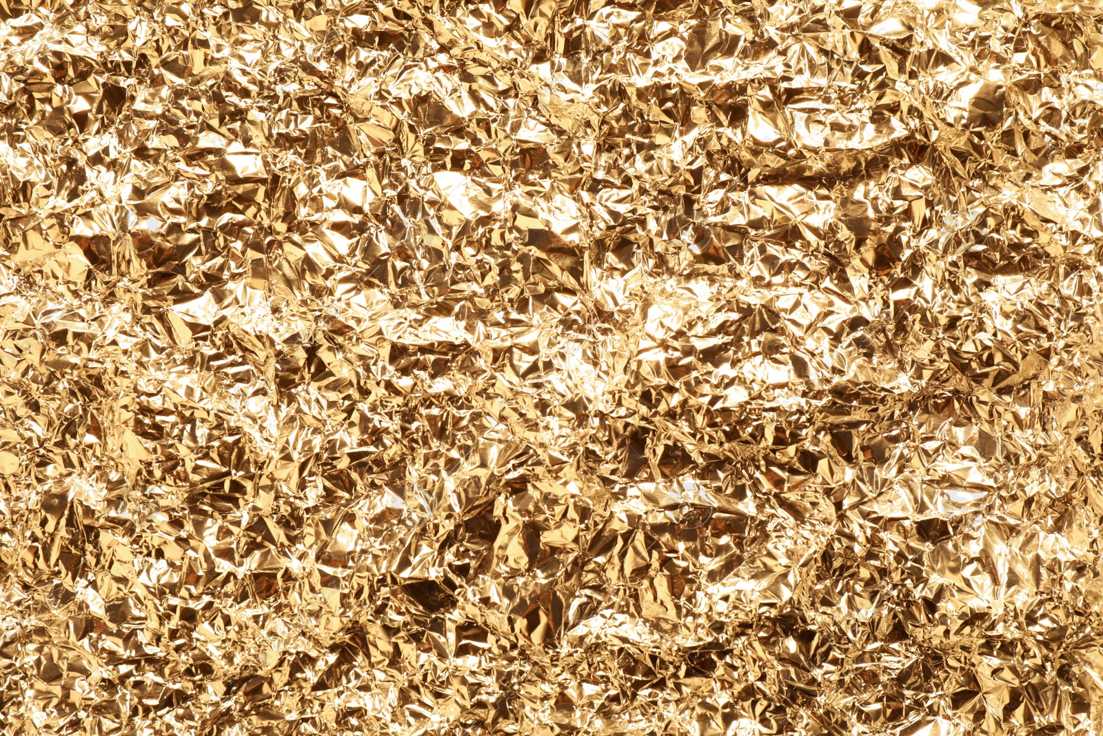 Photo of Crumpled gold foil as background, top view