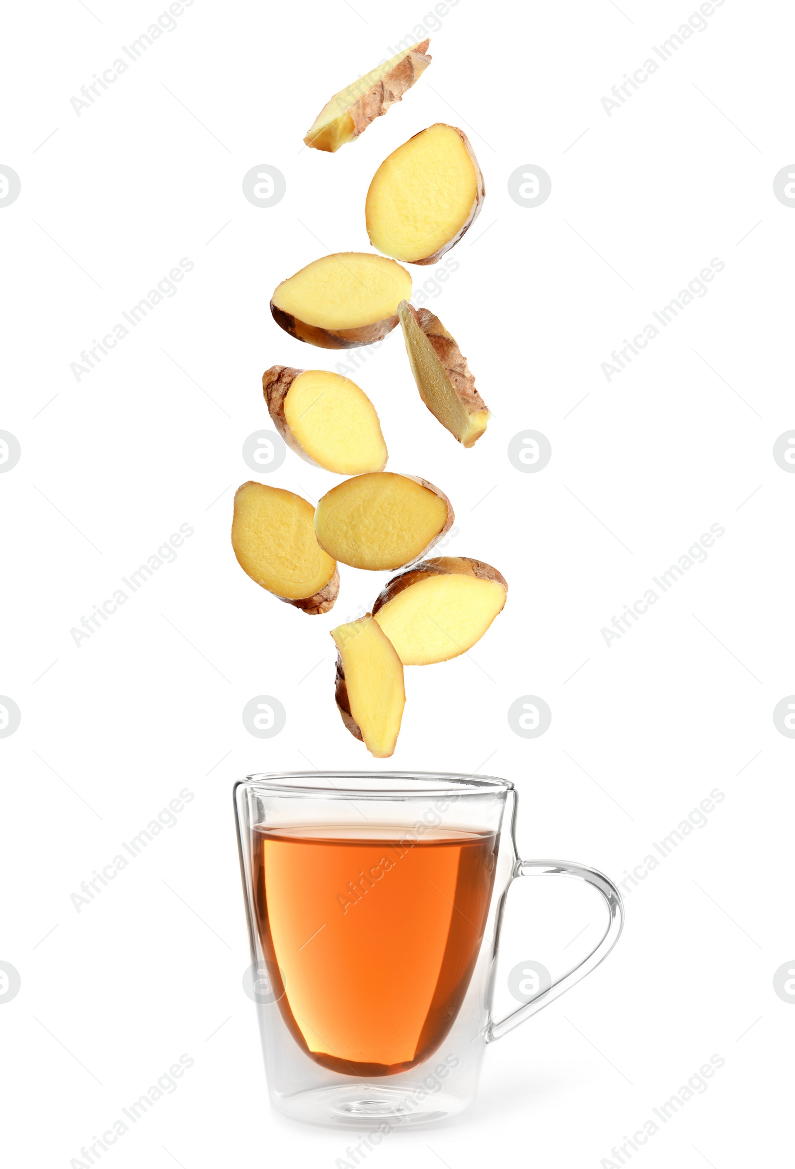 Image of Fresh sliced ginger falling into glass cup of tea on white background