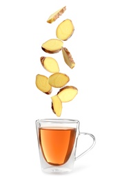 Image of Fresh sliced ginger falling into glass cup of tea on white background