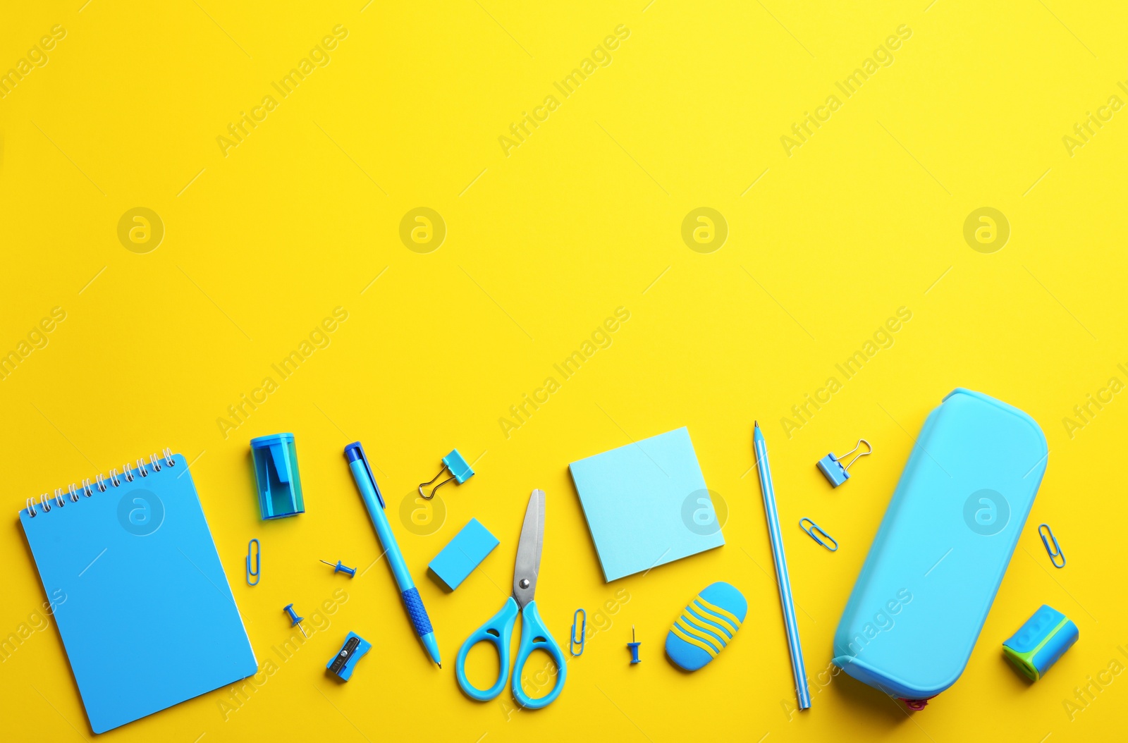 Photo of Light blue school stationery on yellow background, flat lay. Space for text