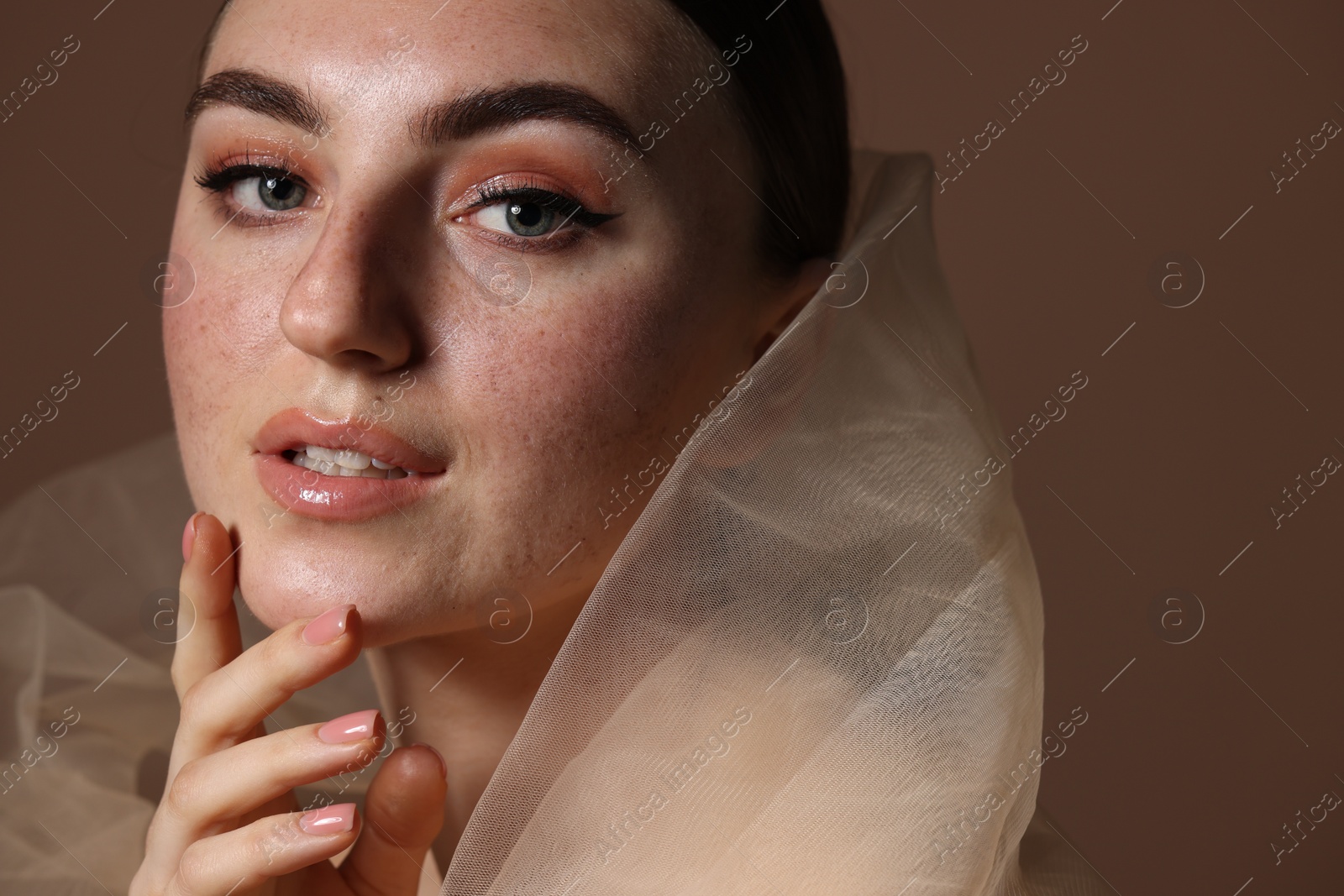 Photo of Fashionable portrait of beautiful woman with fake freckles on brown background, closeup