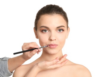 Photo of Visage artist applying makeup on woman's face against white background. Professional cosmetic products