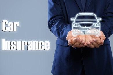 Image of Man demonstrating image of auto on grey background, closeup. Car insurance