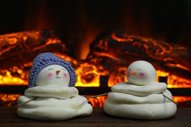 Cute decorative snowmen on wooden floor near fireplace