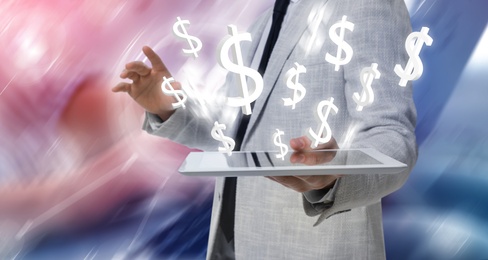 Image of Money exchange concept. Businessman with tablet computer on blurred background, closeup. Dollar currency symbols over device