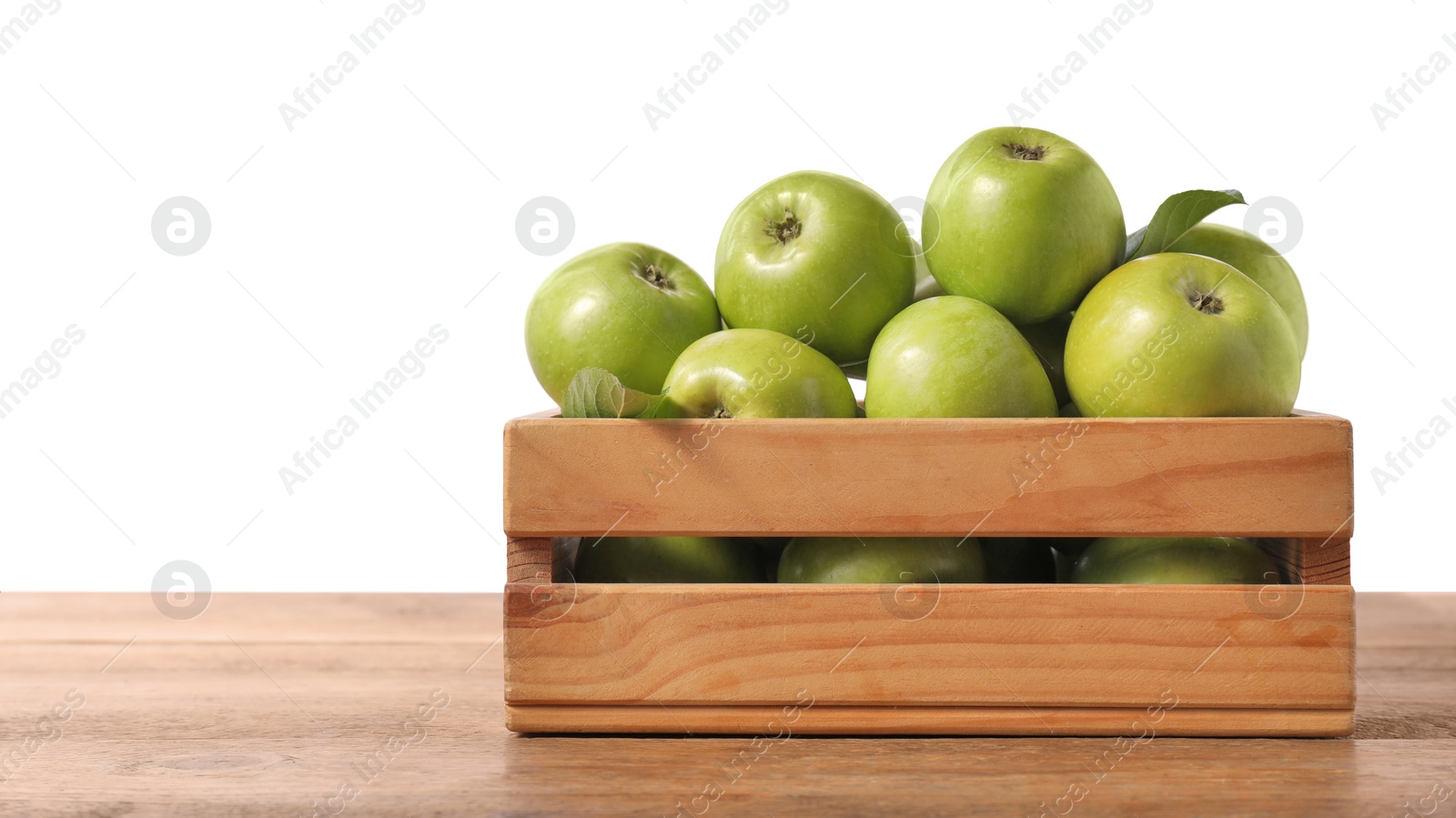 Photo of Ripe green apples in crate on wooden table against white background. Space for text