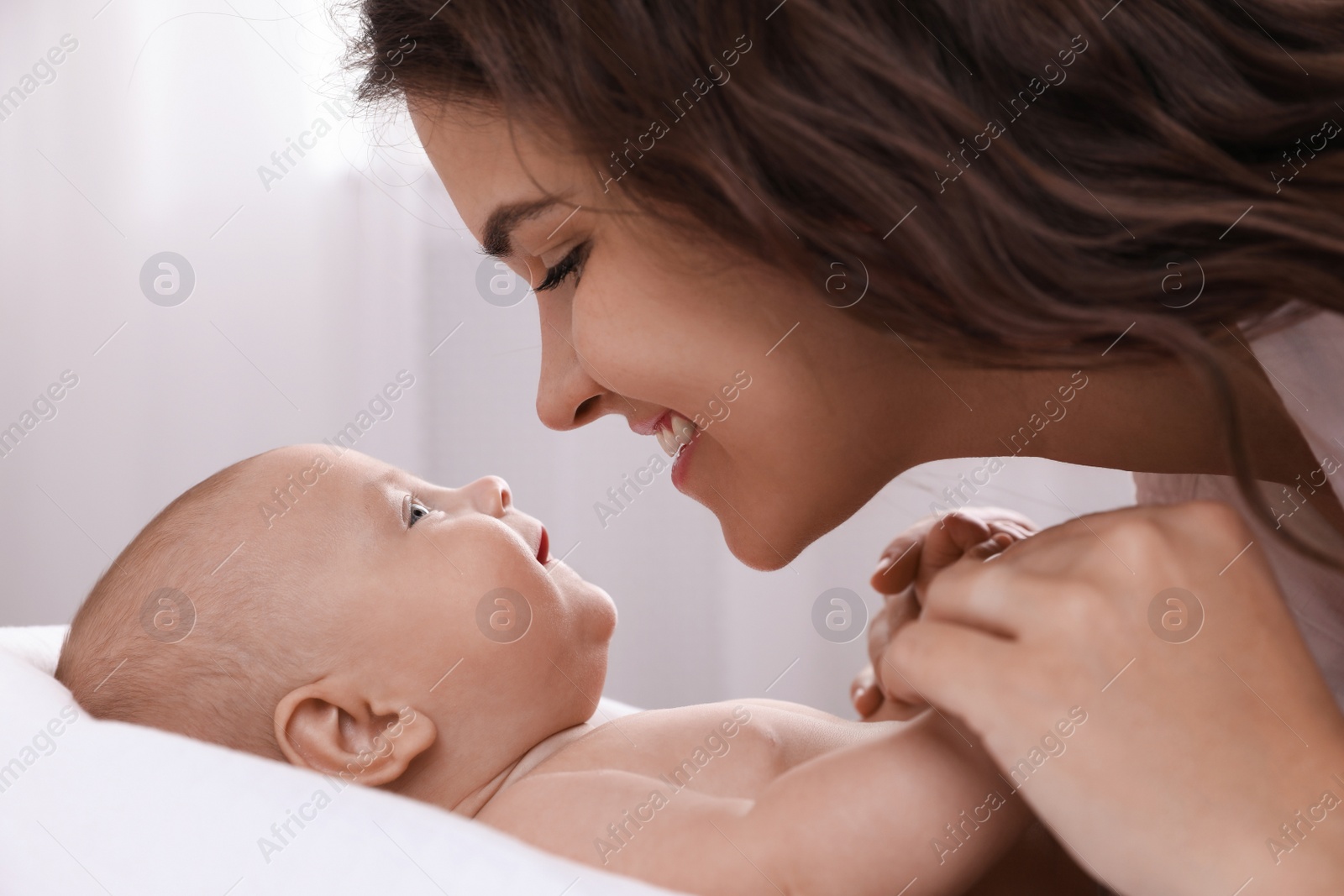 Photo of Happy young mother with her cute baby on bed at home, closeup