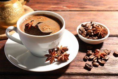 Aromatic hot coffee with anise stars and beans on wooden table