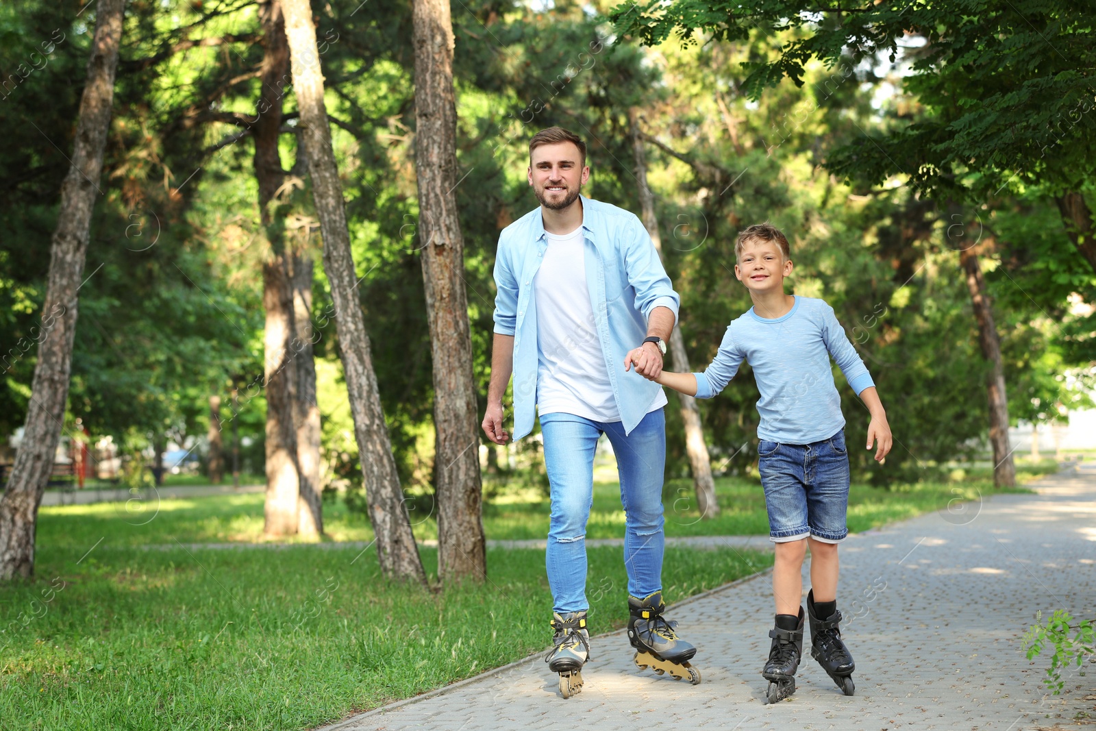 Photo of Father and son roller skating in summer park