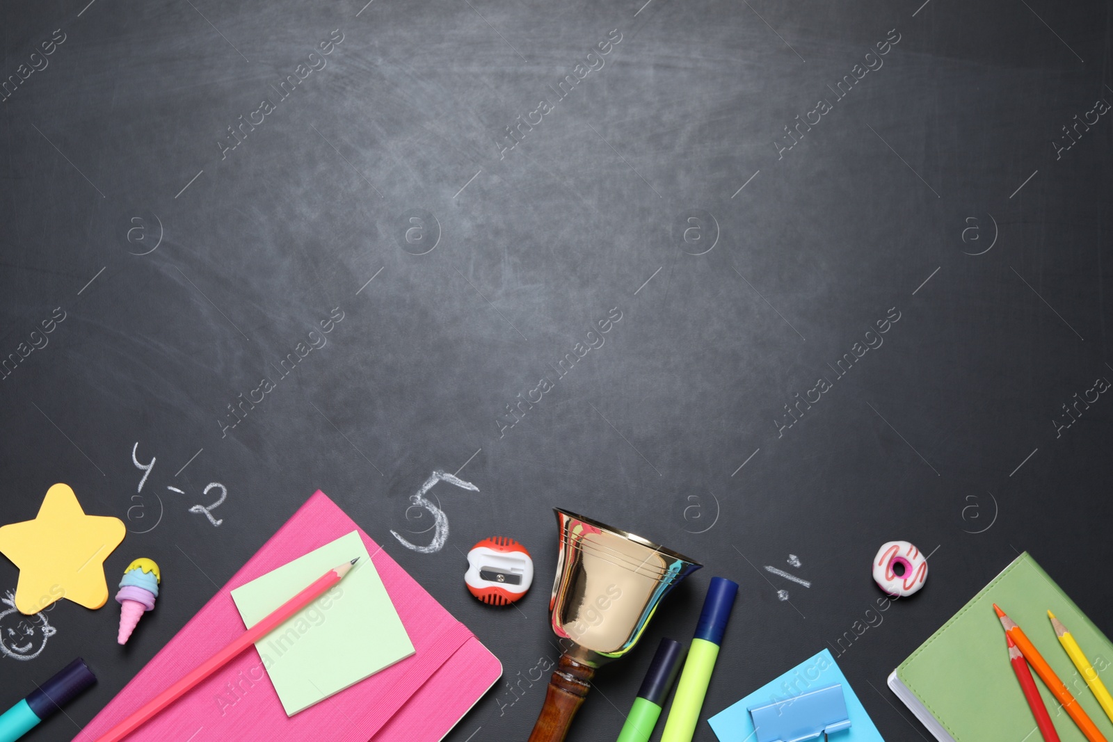 Photo of Flat lay composition with golden bell and school stationery on blackboard, space for text