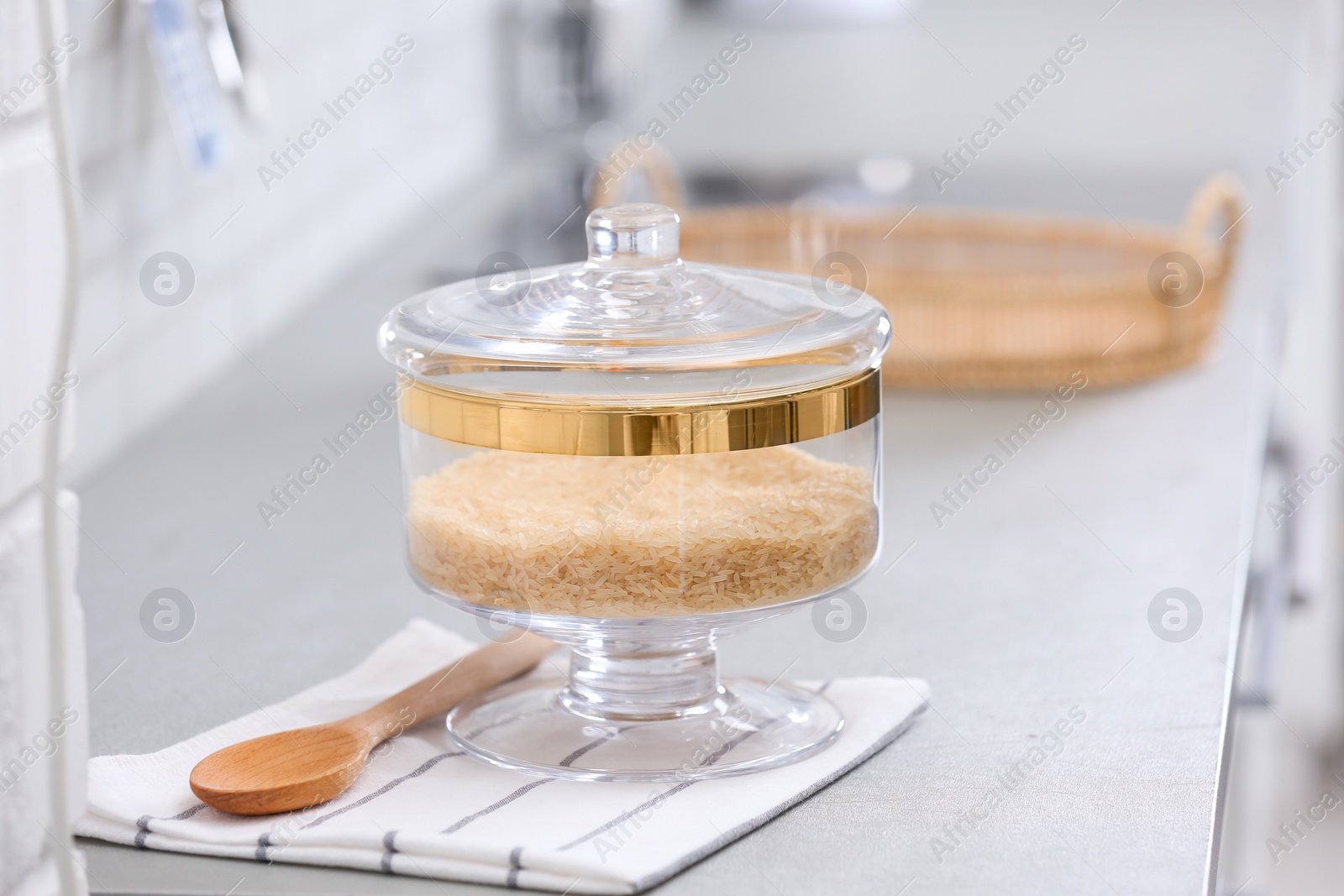 Photo of Jar of raw rice on light grey table in modern kitchen