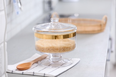 Photo of Jar of raw rice on light grey table in modern kitchen