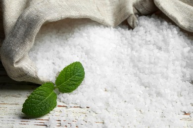 Photo of Bags with natural sea salt on white wooden table, closeup