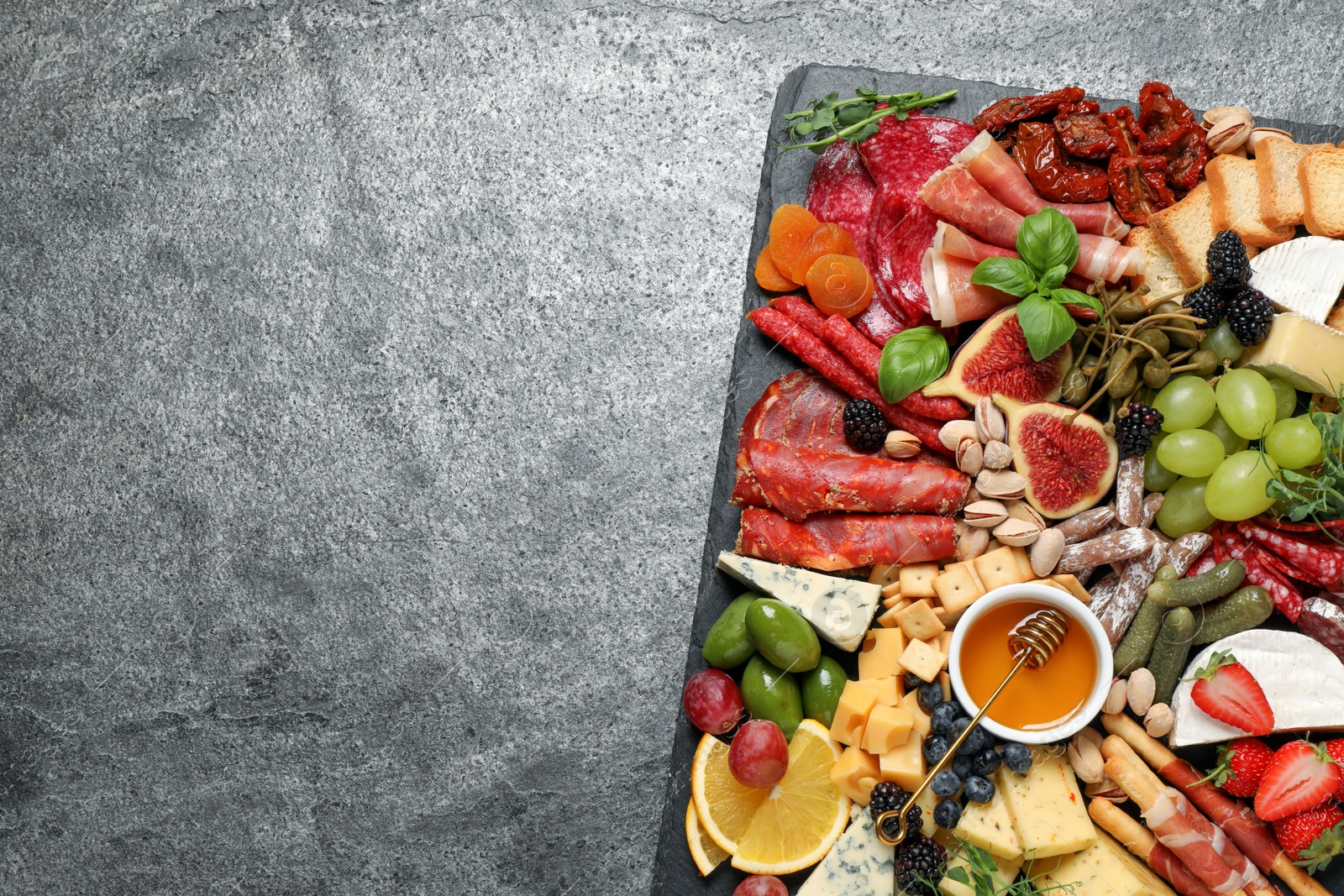 Photo of Set of different delicious appetizers served on grey table, top view. Space for text