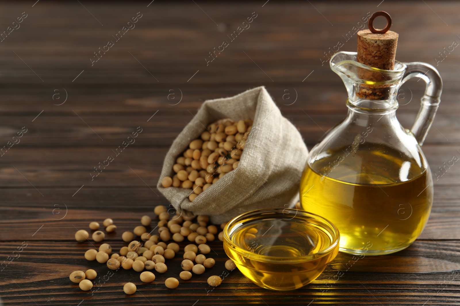 Photo of Composition with soybean oil on wooden table, space for text