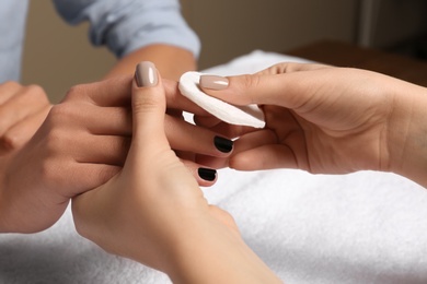 Photo of Manicurist removing polish from client's nails in salon, closeup