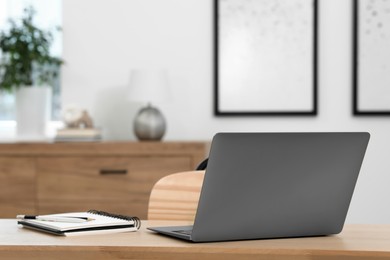 Photo of Home workspace. Laptop and stationery on wooden desk in room