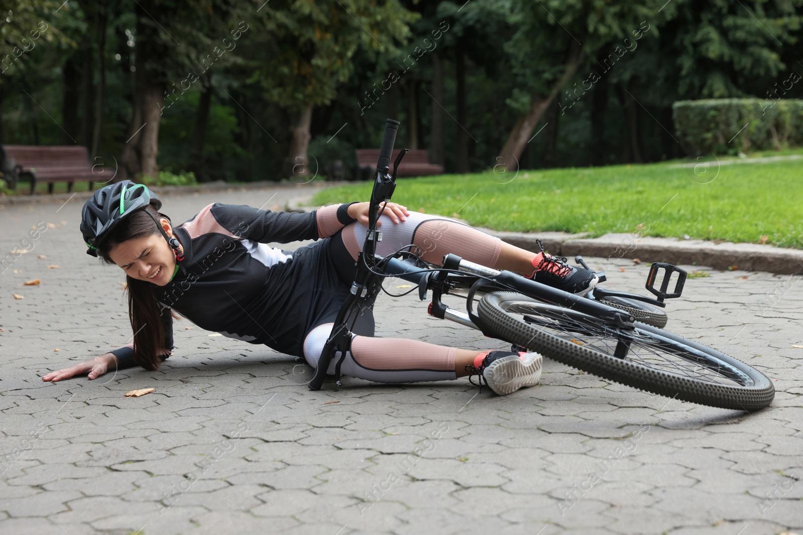 Photo of Young woman fallen off her bicycle in park