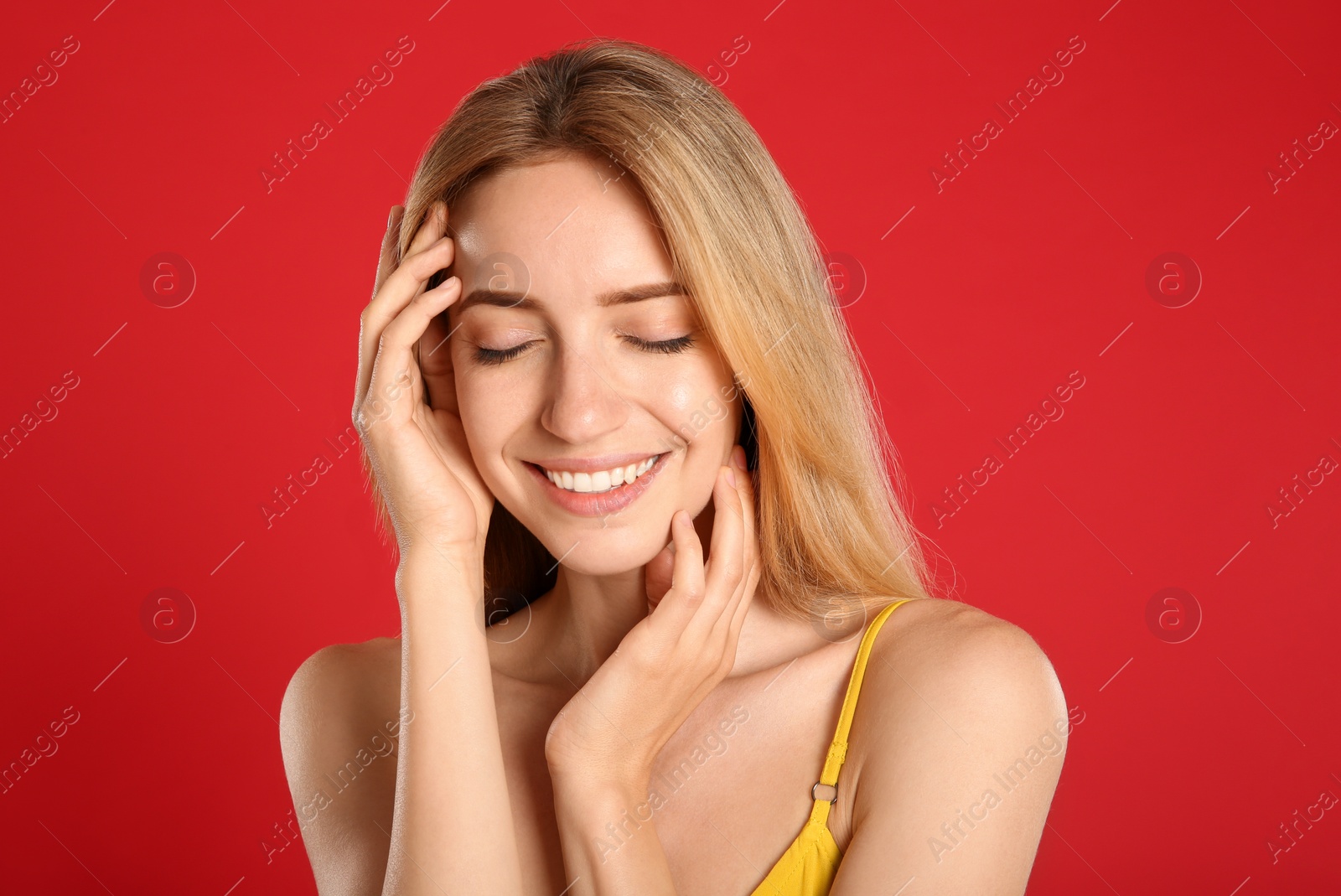 Photo of Portrait of beautiful young woman with blond hair on red background