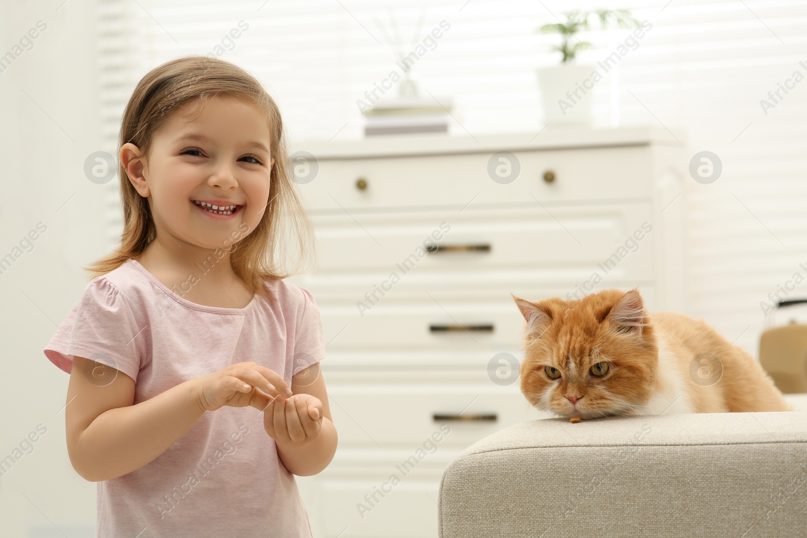 Photo of Happy little girl with cute cat at home