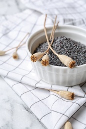 Bowl with dry poppy heads and seeds on table