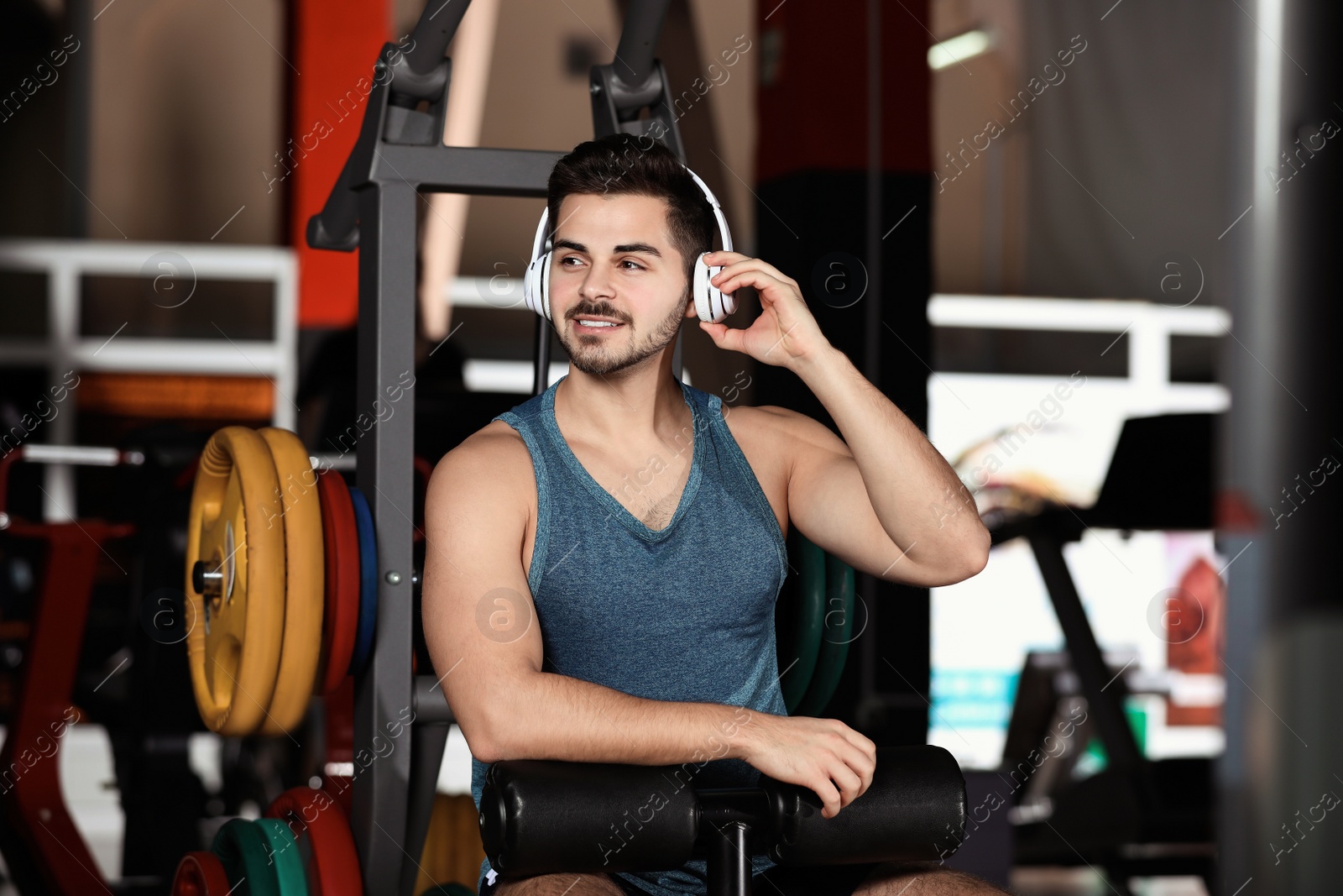 Photo of Young man listening to music with headphones at gym