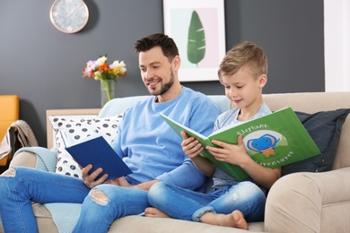 Little boy and his dad reading books at home