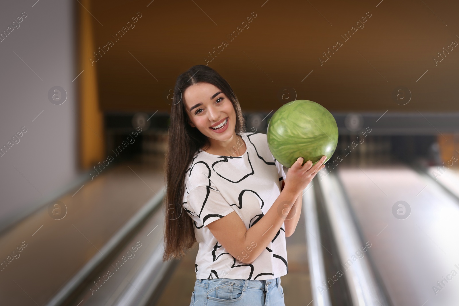 Photo of Young woman with ball in bowling club